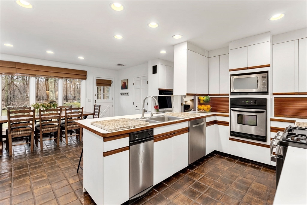 21 Gail Road Weston, MA 02493 - Photo 16 of 37 a kitchen with stainless steel appliances granite countertop a stove top oven a sink dishwasher a dining table and chairs with wooden floor