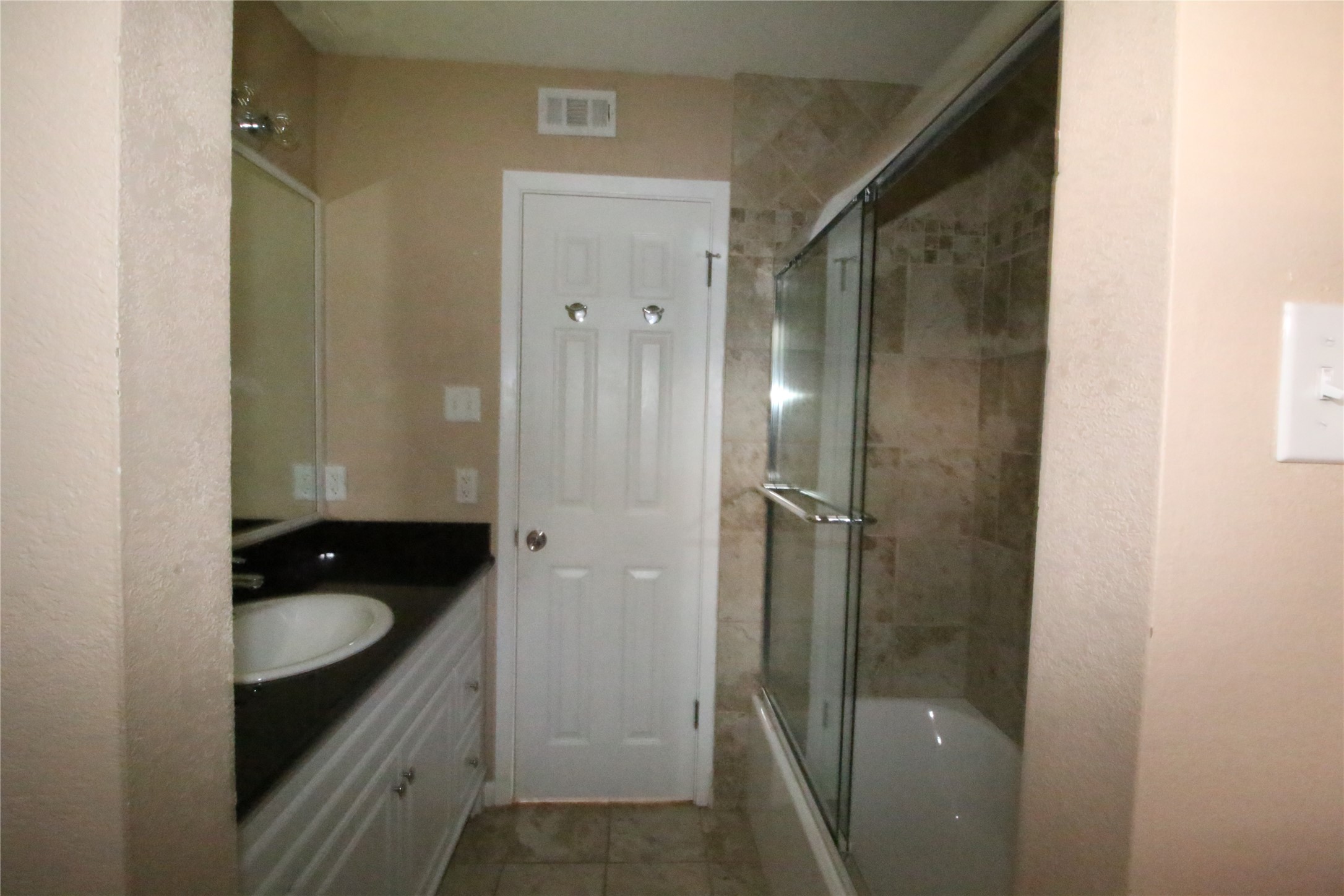 703 Castle Ridge Road, Unit B Austin, TX 78746 - Photo 4 of 5 A well-appointed bath features a sleek glass-enclosed shower-tub combination and ample vanity space.
