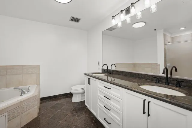 a bathroom with a granite countertop sink a toilet and bathtub