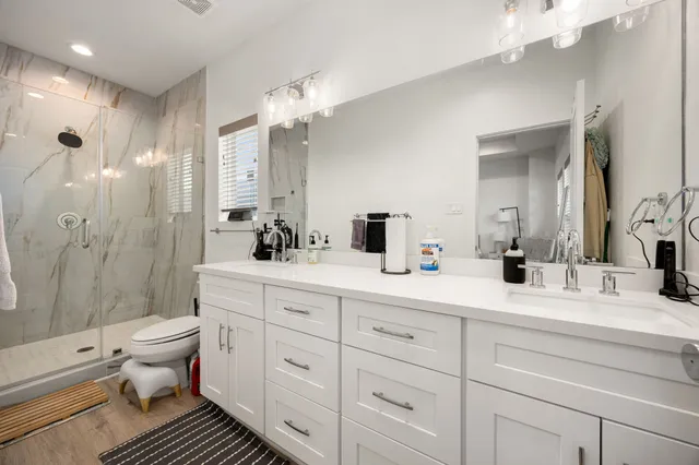 a bathroom with a double vanity sink toilet and shower