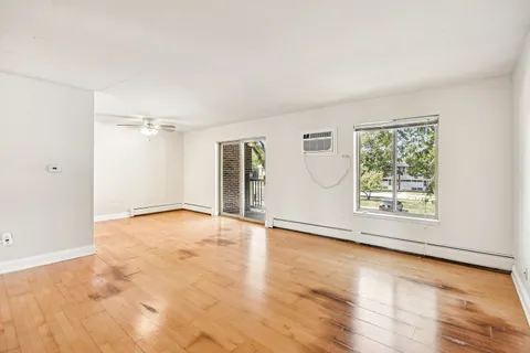 an empty room with wooden floor and windows