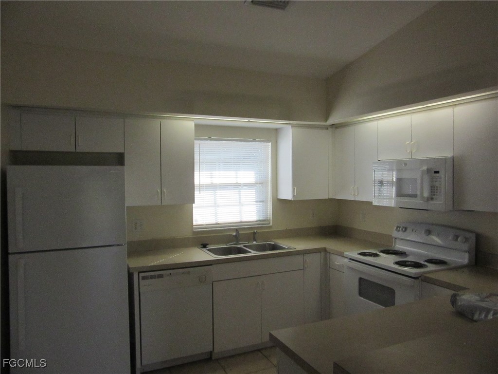 4544-4546 28th Street Southwest Lehigh Acres, FL 33973 - Photo 4 of 23 a kitchen with a refrigerator stove and sink