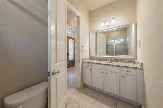 a spacious bathroom with a granite countertop sink a toilet mirror and vanity