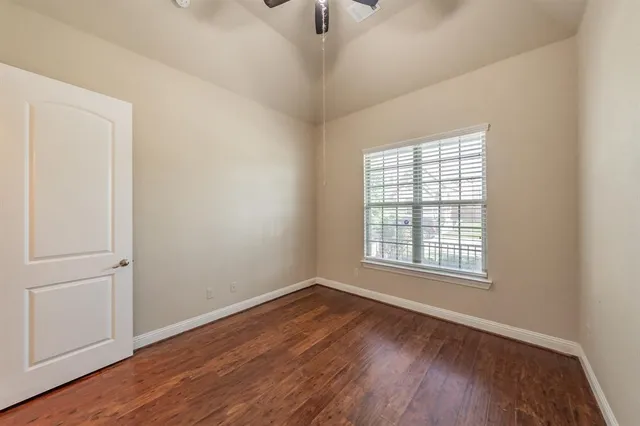 an empty room with wooden floor cabinet and windows