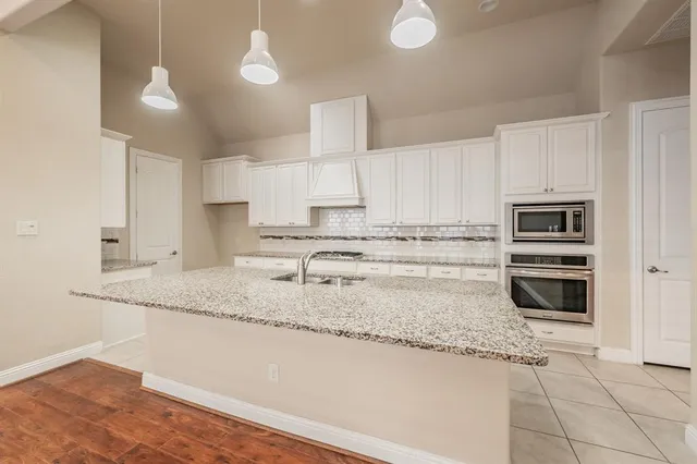 a kitchen with granite countertop a sink a stove and cabinets