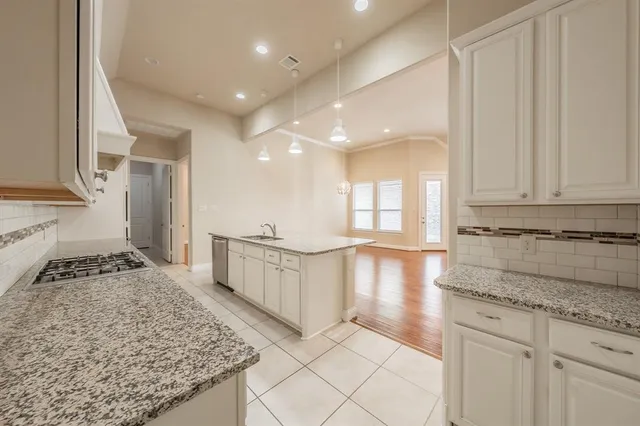 a view of a kitchen with kitchen island granite countertop wooden cabinets a sink and a counter top space