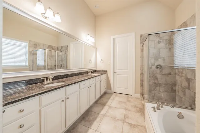 a large bathroom with a granite countertop double vanity sink a mirror and a shower
