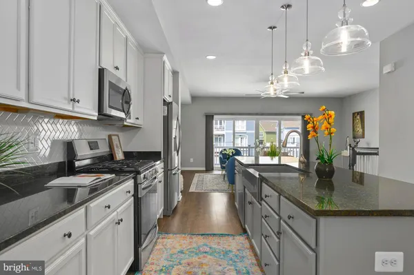 a kitchen with stainless steel appliances granite countertop a sink a stove and a wooden floors