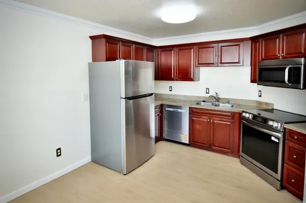 a kitchen with stainless steel appliances granite countertop a stove top oven a refrigerator and a sink with wooden cabinets