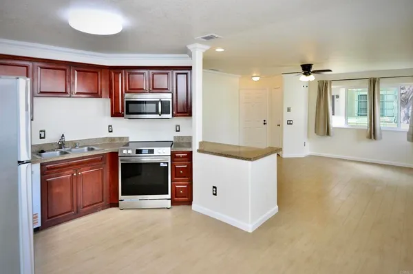 a large kitchen with stainless steel appliances granite countertop a stove a sink and a refrigerator