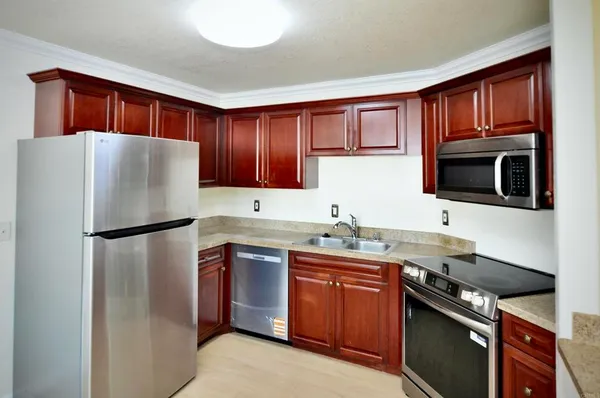 a white refrigerator freezer sitting inside of a kitchen with stainless steel appliances granite countertop a refrigerator stove a sink dishwasher and microwave oven