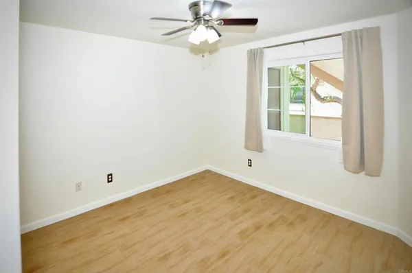 an empty room with a window and a fan