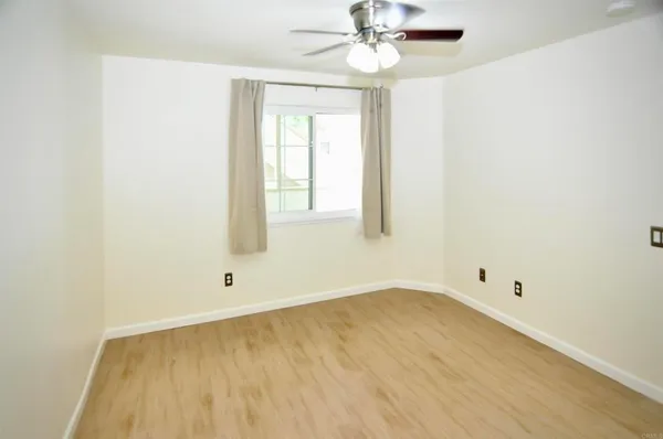 an empty room with a window and a fan