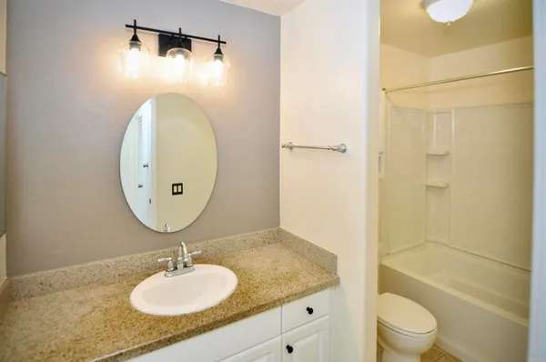 a bathroom with a granite countertop sink toilet mirror vanity and shower