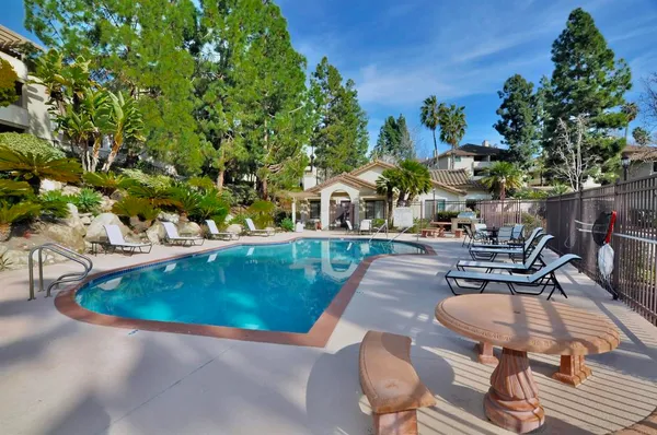 a view of a swimming pool with lawn chairs potted plants