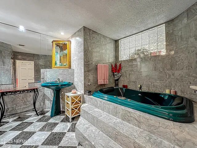 a large bedroom with a large bed a chandelier and next to a window