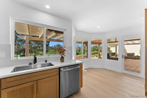 a living room with stainless steel appliances granite countertop a sink and a large window