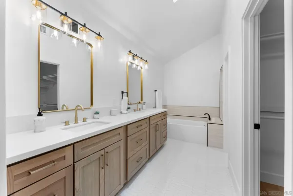 a bathroom with a double vanity sink toilet mirror and bathtub
