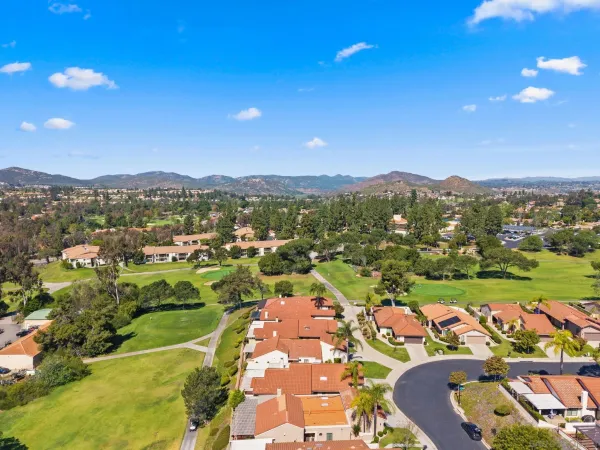 an aerial view of residential houses with outdoor space and trees