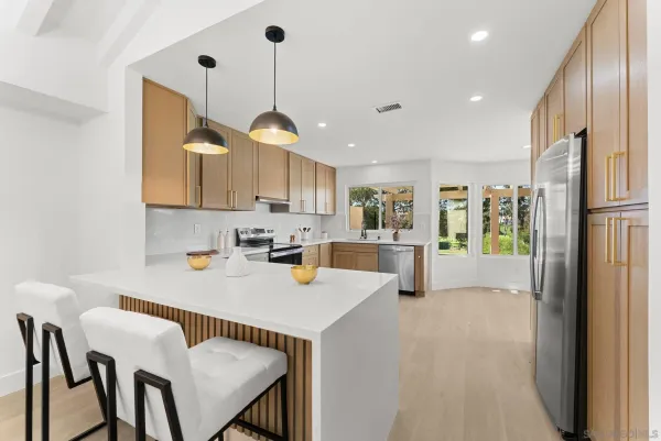 a kitchen with stainless steel appliances granite countertop a refrigerator a sink a stove and white cabinets with wooden floor