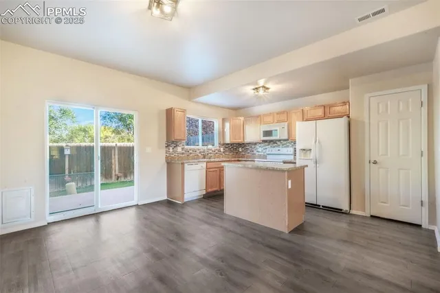 a kitchen with a refrigerator and wooden cabinets