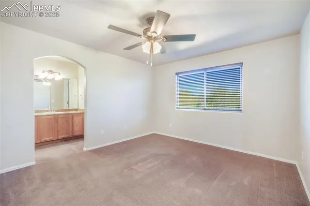 an empty room with chandelier fan and windows