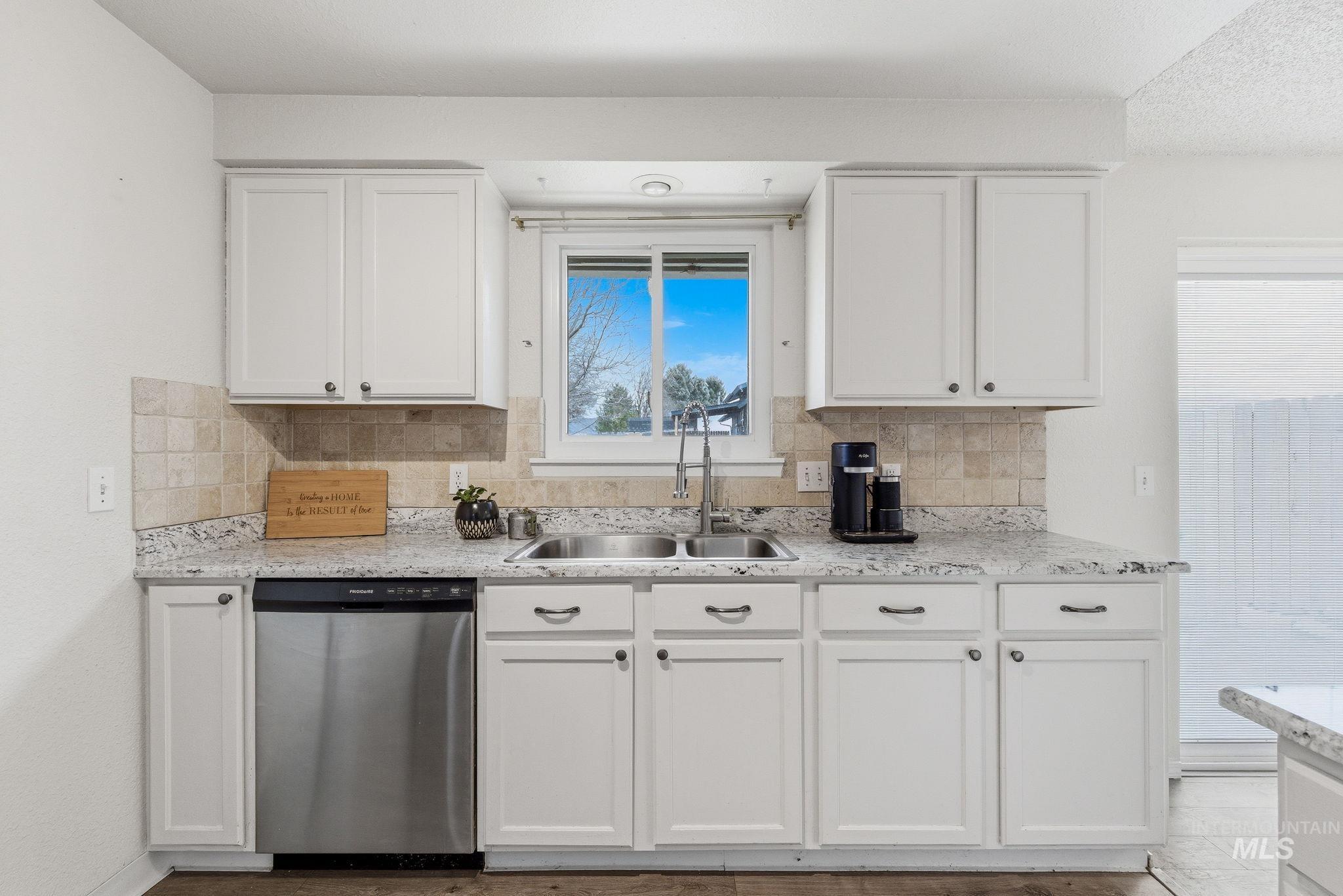 598 Easy Street Kuna, ID 83634 - Photo 17 of 50 Kitchen featuring white cabinets, stainless steel dishwasher, tasteful backsplash, and light stone countertops