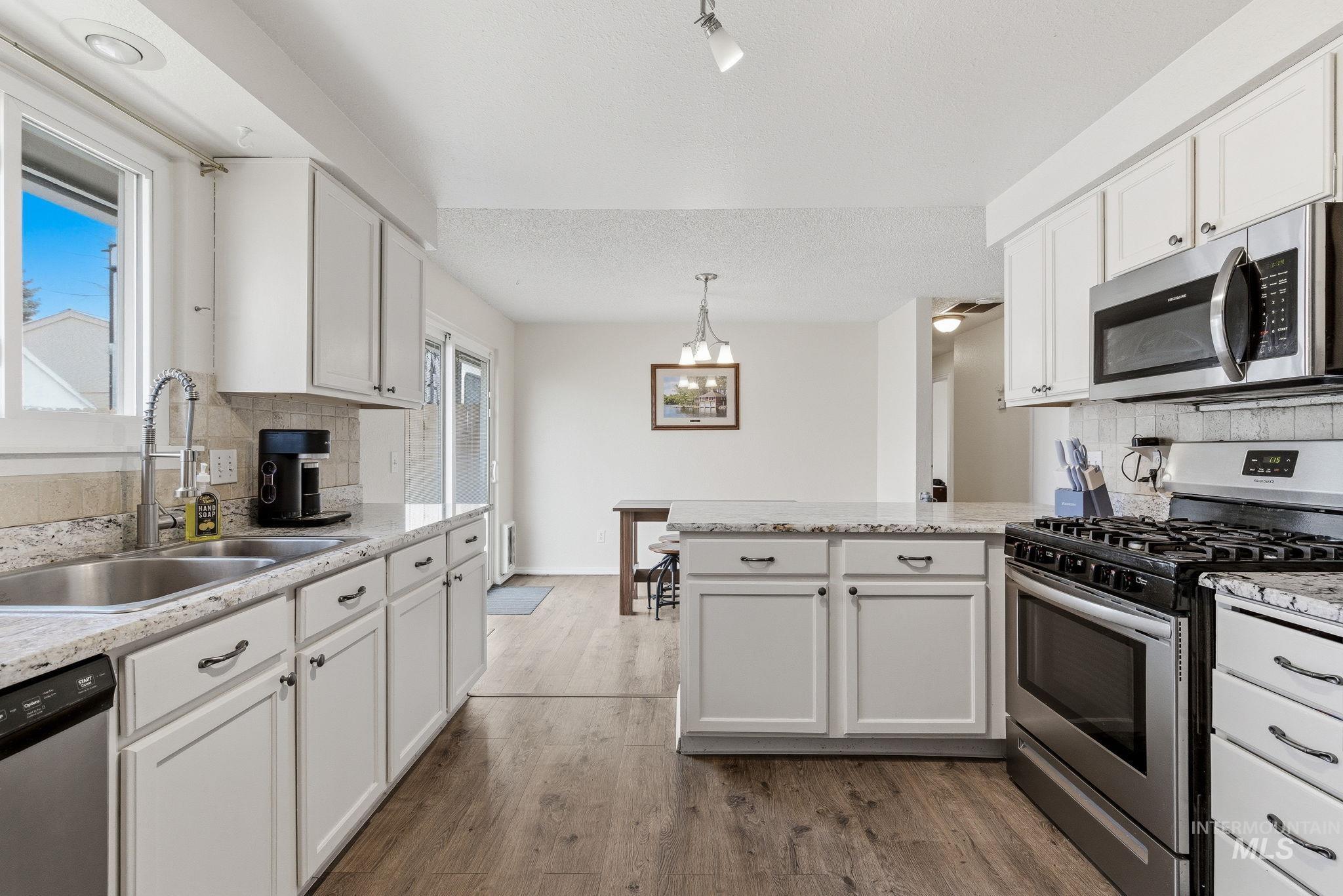 598 Easy Street Kuna, ID 83634 - Photo 21 of 50 Kitchen with stainless steel appliances, decorative backsplash, a peninsula, and white cabinetry