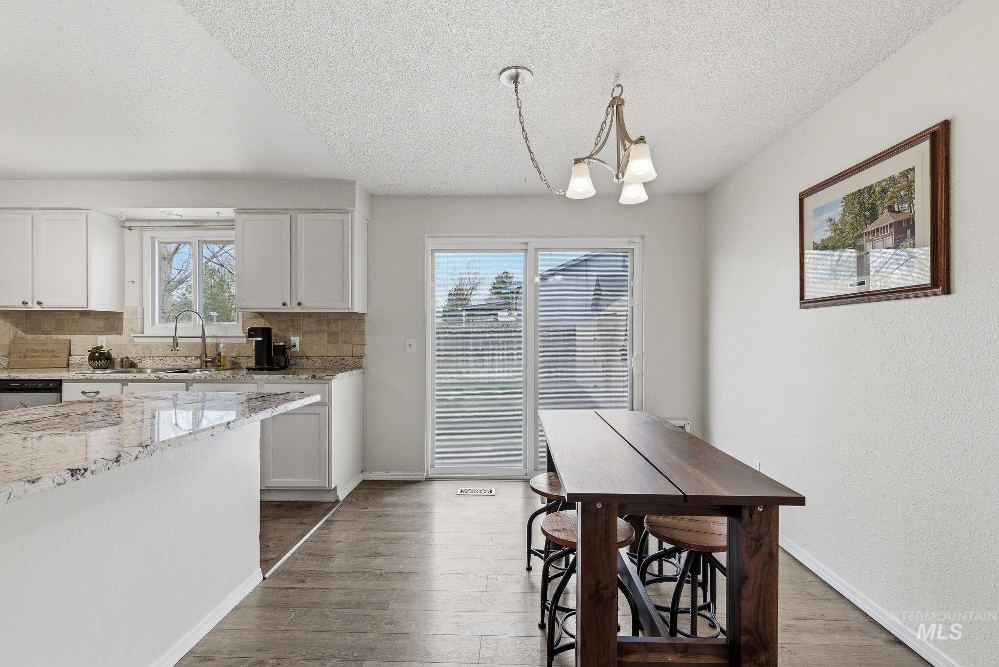 598 Easy Street Kuna, ID 83634 - Photo 24 of 50 Kitchen with light stone countertops, white cabinetry, dark wood finished floors, and a textured ceiling