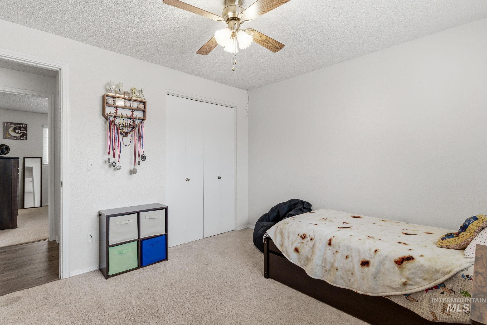 598 Easy Street Kuna, ID 83634 - Photo 30 of 50 Carpeted bedroom with a textured ceiling, a closet, and a ceiling fan