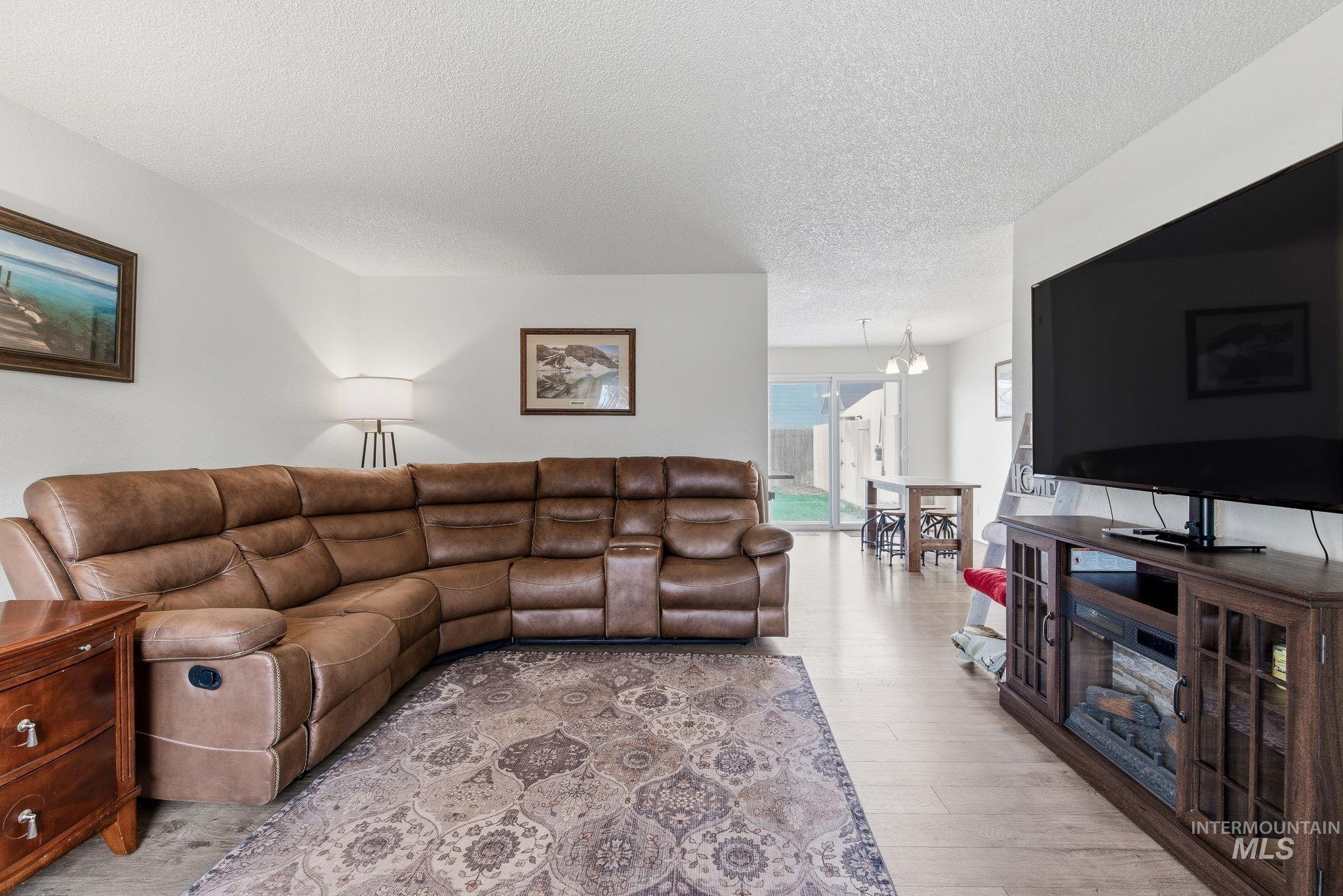 598 Easy Street Kuna, ID 83634 - Photo 9 of 50 Living room featuring a textured ceiling, light wood-style floors, and suspended lighting
