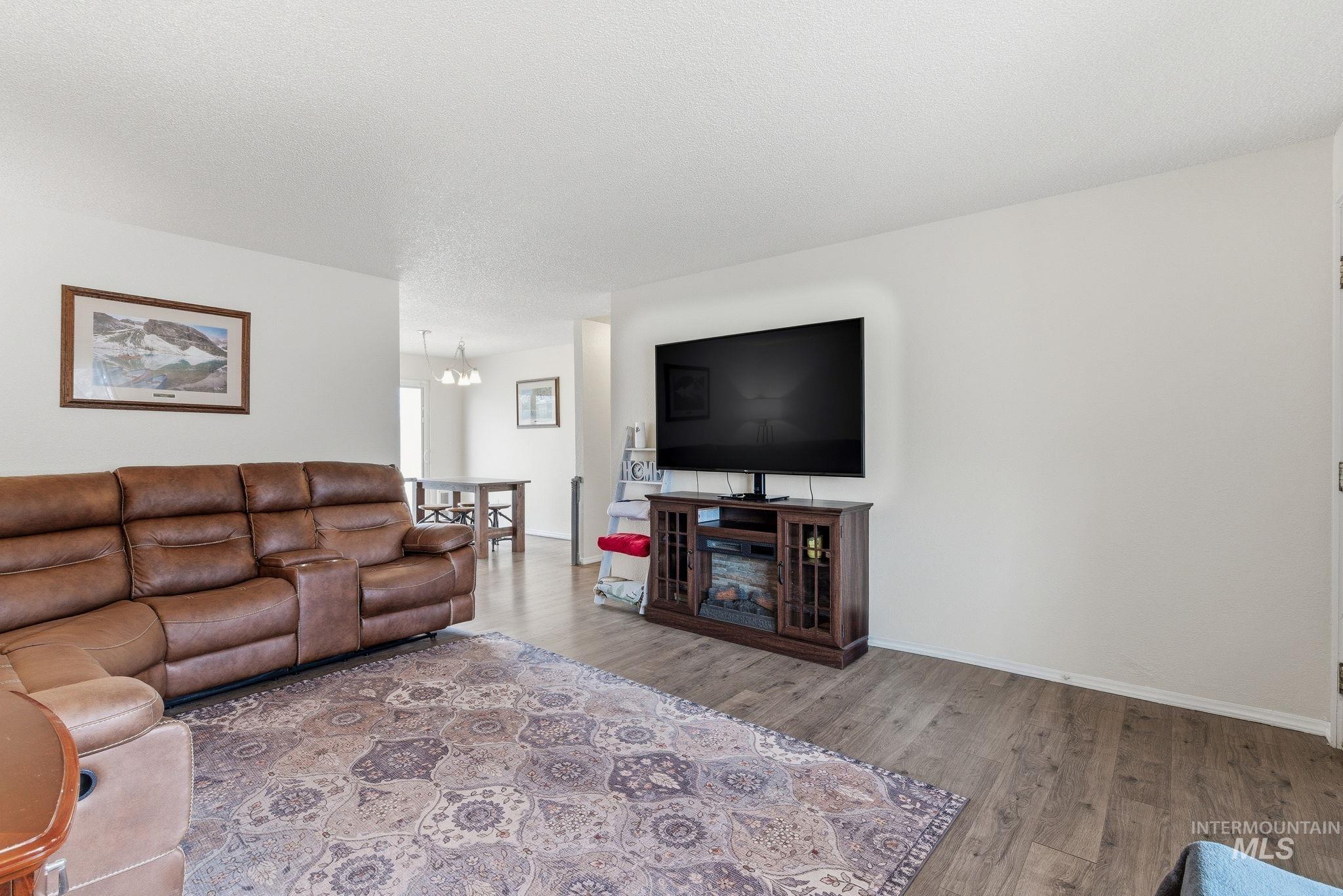 598 Easy Street Kuna, ID 83634 - Photo 10 of 50 Living room featuring light wood-style flooring, a chandelier, and a textured ceiling