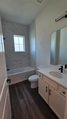 a bathroom with a granite countertop sink toilet a large mirror a bathtub and shower