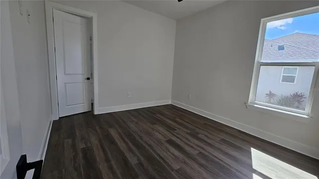 a view of an empty room with wooden floor and a window