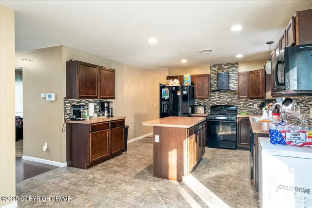 a kitchen with stainless steel appliances kitchen island granite countertop a sink stove and refrigerator