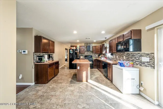 a kitchen with stainless steel appliances kitchen island granite countertop a stove refrigerator and a sink