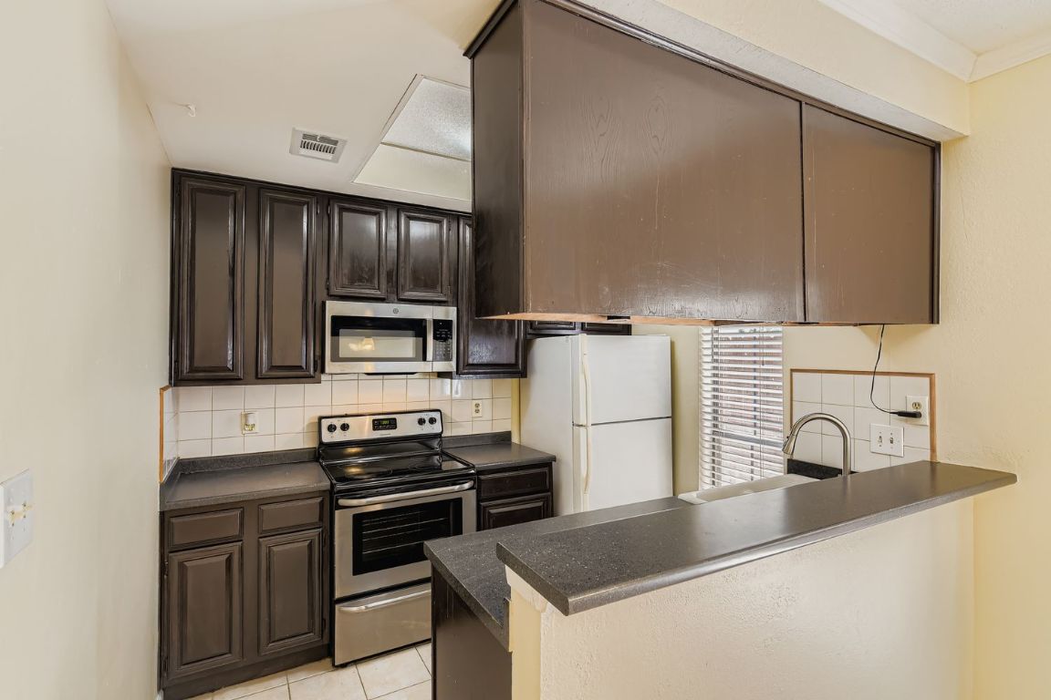 708 Graham Place, Unit 101 Austin, TX 78705 - Photo 3 of 12 a kitchen with a sink a stove and refrigerator