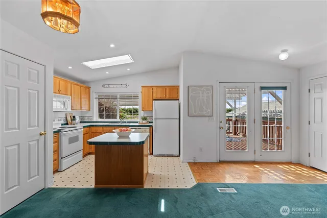 a open kitchen with stainless steel appliances granite countertop a stove a sink dishwasher and a refrigerator with wooden floor