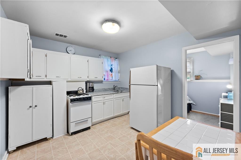 33 Prospect Lane Colonia, NJ 07067 - Photo 26 of 35 a kitchen with a refrigerator a stove top oven and white cabinets