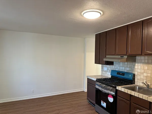 a kitchen with granite countertop a stove and a wooden cabinets