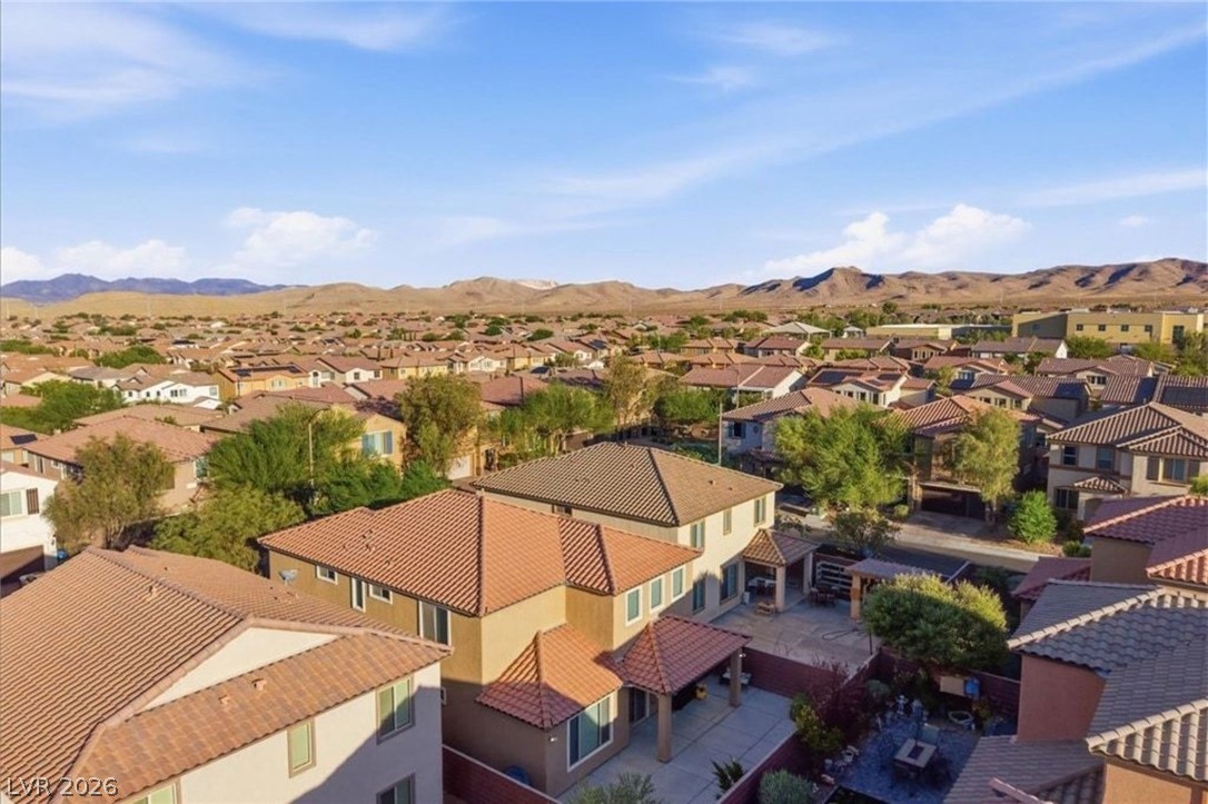 11009 Prairie Grove Road Las Vegas, NV 89179 - Photo 43 of 49 An aerial perspective showcases a residential neighborhood nestled against a backdrop of distant mountains under a broad sky.