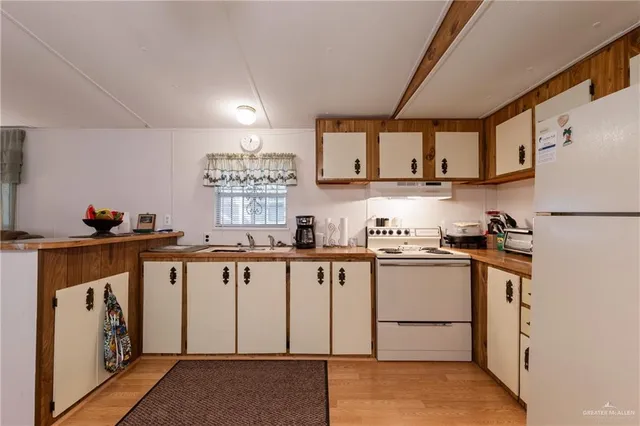a kitchen with granite countertop a sink a stove a refrigerator and white cabinets