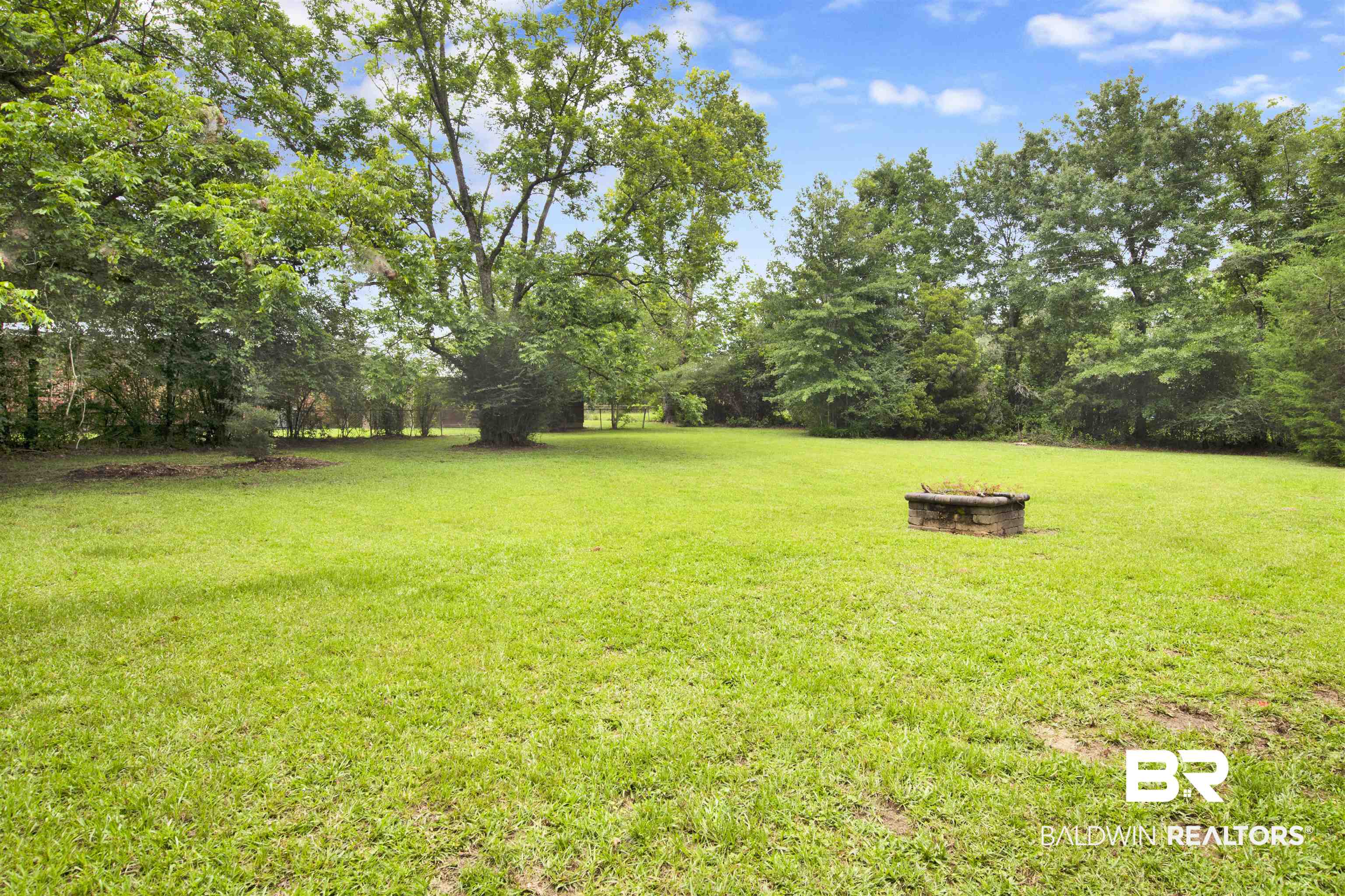 17714 Horseneck Road Bay Minette, AL 36507 - Photo 30 of 36 Expansive grassy yard area featuring mature trees and a stone-built fire pit