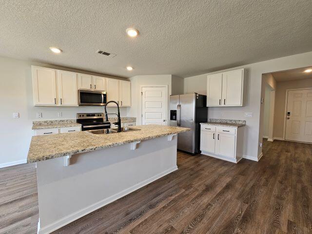 320 Flounder Street Crestview, FL 32539 - Photo 12 of 41 a large kitchen with granite countertop a stove a sink a refrigerator and white cabinets with wooden floor