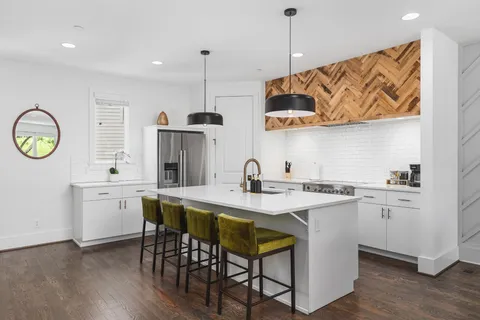 a kitchen with stainless steel appliances granite countertop a sink a stove a refrigerator and island with wooden floor