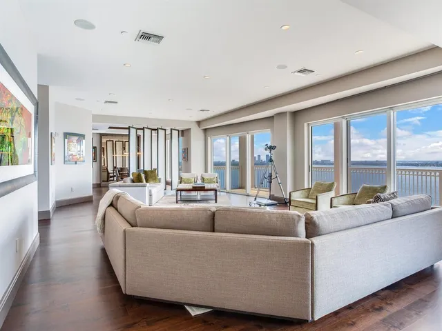 a living room with furniture a large window and wooden floor