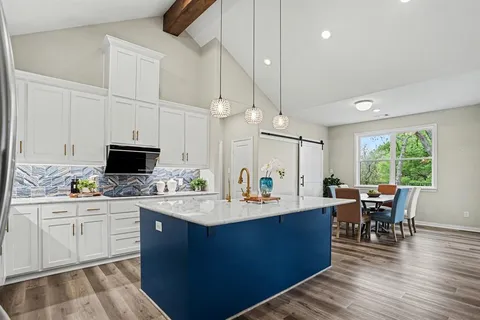 a view of a kitchen with kitchen island a island a sink a window and stainless steel appliances