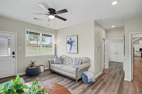 a living room with stainless steel appliances furniture and a wooden floor