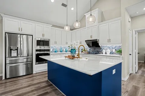 a kitchen with kitchen island a sink a microwave a stove and refrigerator