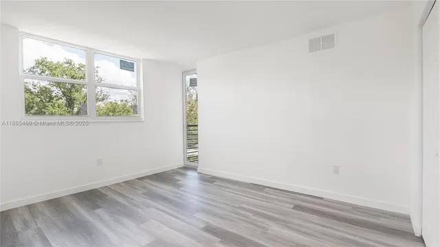 an empty room with wooden floor and window